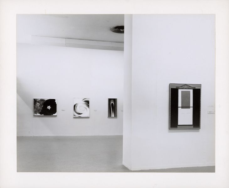 White gallery walls. A half wall in the foreground has a rectangular artwork of what seems to be a door. The wall in the background shows three more artworks. All of the artworks are by Georgia O'Keeffe.